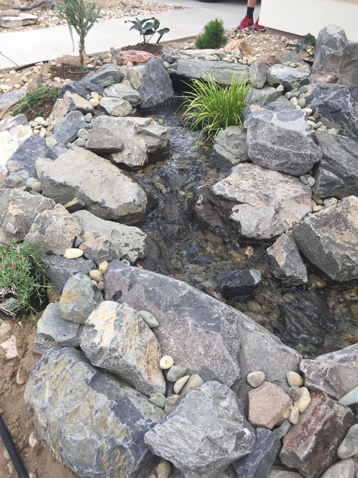 Boulders set along a new stream bed during a pond build