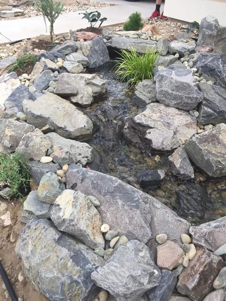 Boulders set along a new stream bed during a pond build
