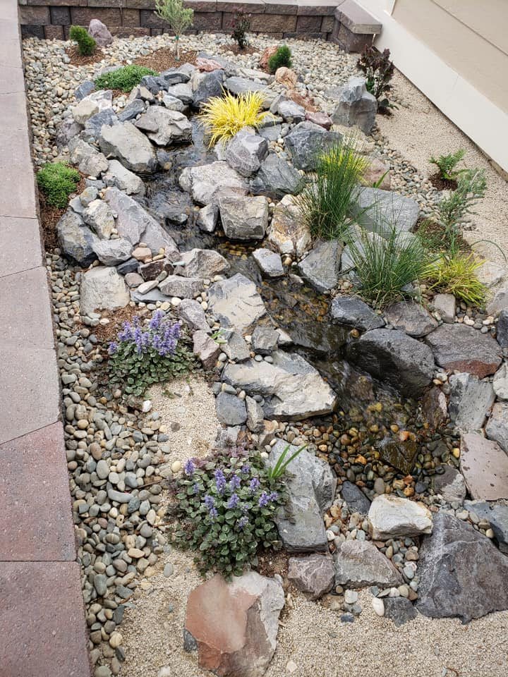 A rock stream bed with flowering plants along a side yard